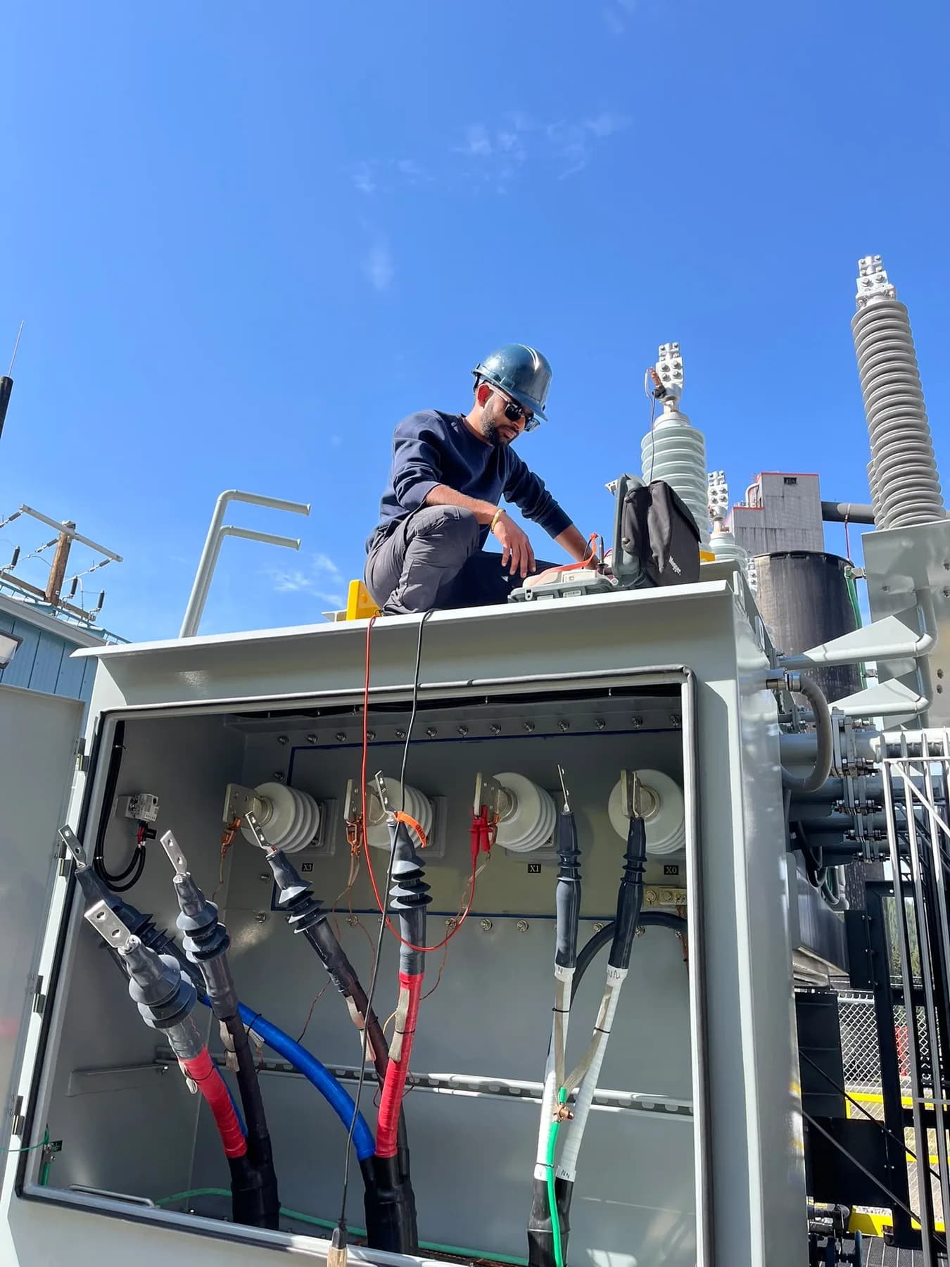 Field technician testing transformer cable terminations during commissioning